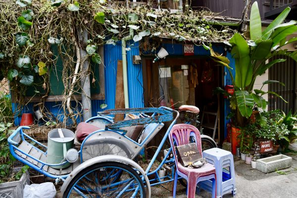 A blue-painted outer wall, tropical plants, and a Vietnamese bicycle taxi, Xich Lo! This corner is already in Vietnam.